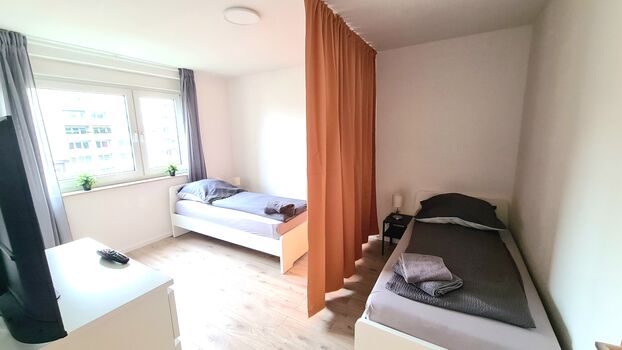 Schlafzimmer mit Einzelbetten und Vorhängen für Privatsphäre Schlafzimmer mit Einzelbetten und Vorhängen für Privatsphäre