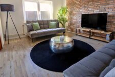 Gemütliches Wohnzimmer mit Schlafcouches und Fernseher – perfekt zum Entspannen nach der Arbeit. Der Raum ist durch eine Trennwand flexibel abtrennbar, ideal für mehr Privatsphäre. Gemütliches Wohnzimmer mit Schlafcouches und Fernseher – perfekt zum Entspannen nach der Arbeit. Der Raum ist durch eine Trennwand flexibel abtrennbar, ideal für mehr Privatsphäre.