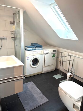 Modernes Duschbad mit Waschmaschine und Trockner 