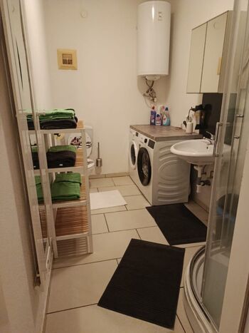 Badezimmer mit Toilette, Dusche, Waschmaschine und Trockner