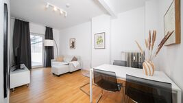 Wohnzimmer mit Sofa, Essbereich und Smart-TV