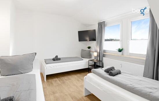 Schlafzimmer mit drei Einzelbetten uns Smart TV