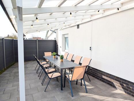 Überdachte Terrasse mit großem Esstisch und Gartenstühle für 10P