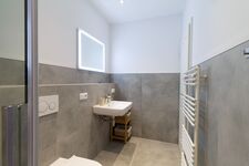 Helles modernes Badezimmer mit Handtüchern und Spiegelbeleuchtung