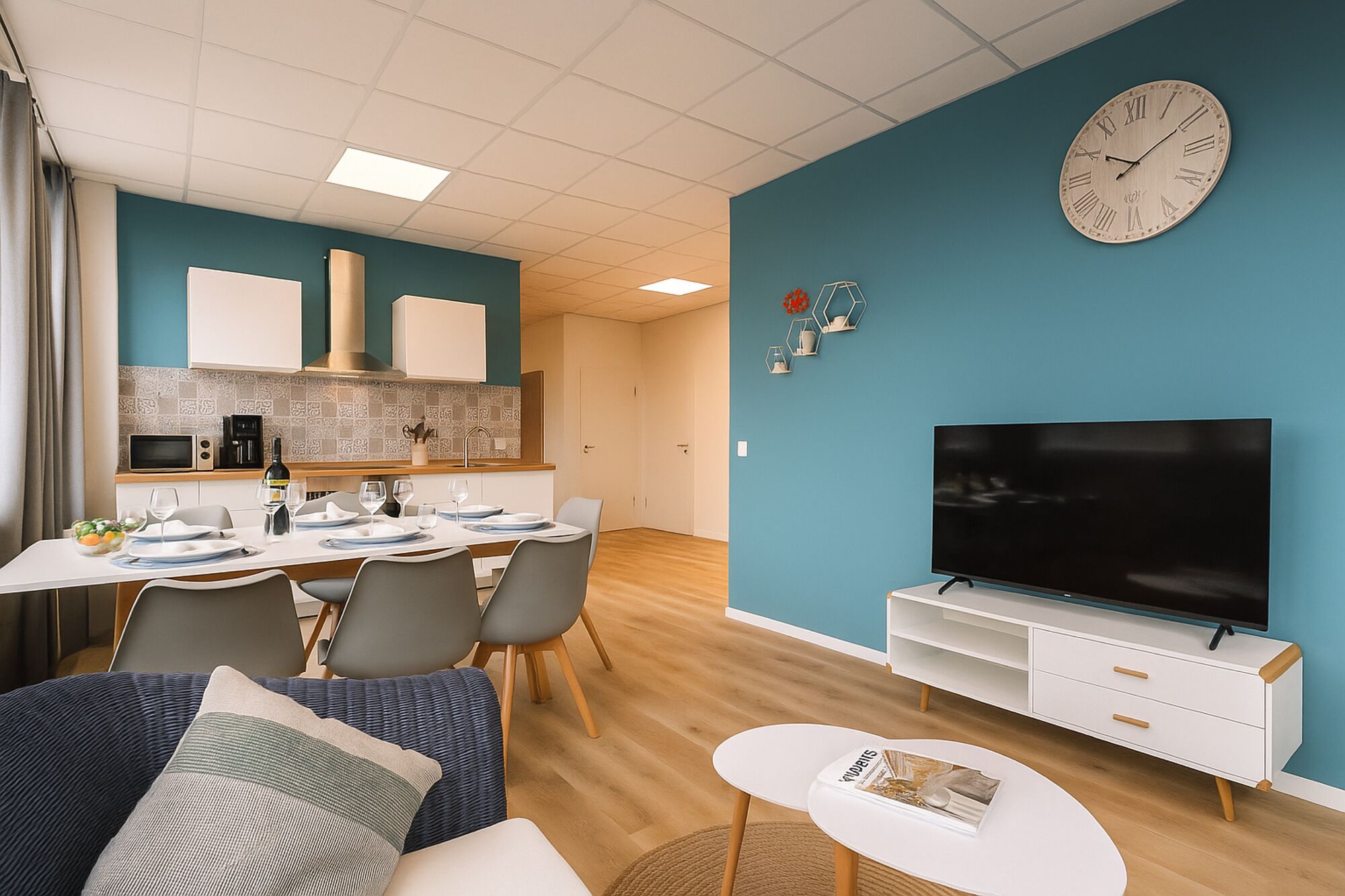 Wohnzimmer mit Fernseher, Esstisch, voll ausgestatteter Küche