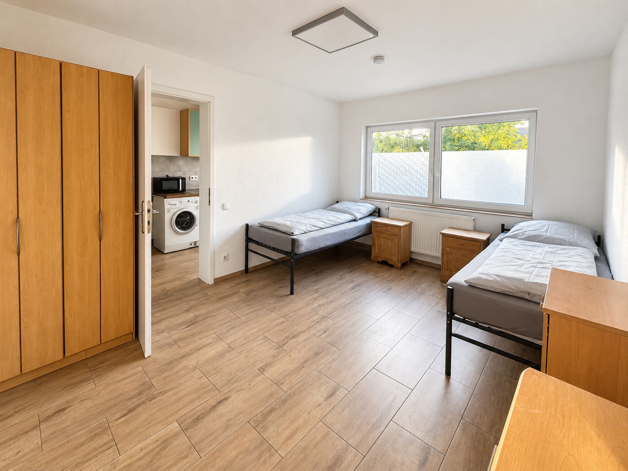 Helles Zimmer mit getrennten Betten, Schrank und Zugang zur Küche