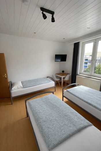 helles Zimmer mit 3 Einzelbetten, Ferseher und Tisch
