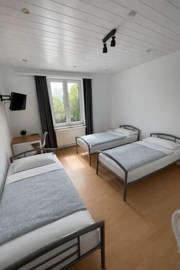 helles Zimmer mit 3 Einzelbetten, Ferseher und Tisch