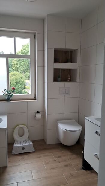 Modern bathroom with shower, bathtub, toilet, hairdryer, iron and ironing board
