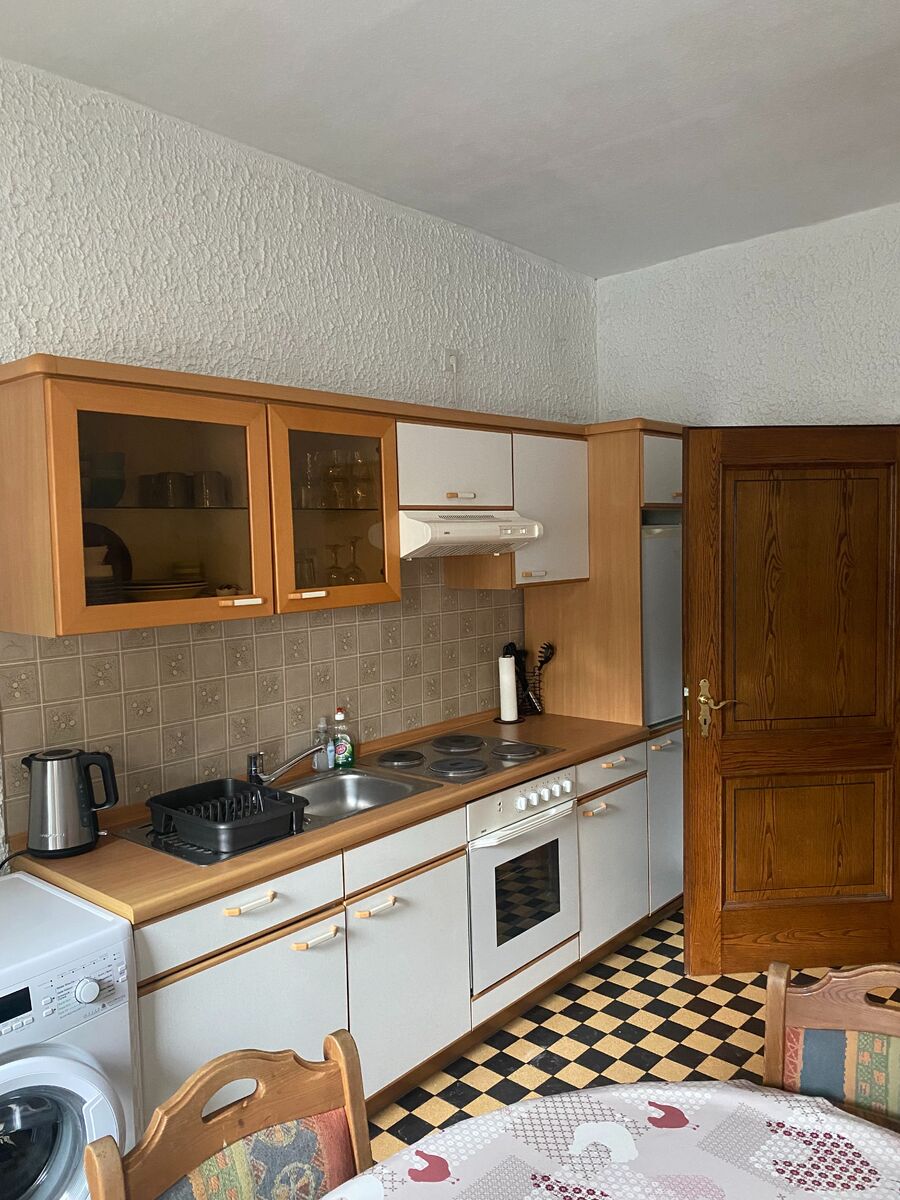 Voll ausgestattete Küche mit Herd, Spühle, Kühlschrank und Kochutensilien sowie ausreichend Geschirr und Besteck.