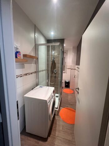 Sauberes, modernes Badezimmer mit Dusche, Waschmaschine und WC. Ideal für den täglichen Gebrauch.