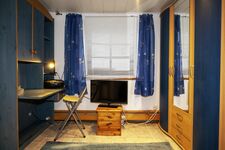 Schreibplatz, Kleiderschrank und Fernseher im Wohnraum