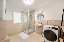 Helles Bad mit Dusche, Waschbecken und Waschtrockner, Haartrockner und Bügelzubehör