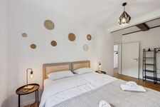 Schlafzimmer 1 mit hochwertigen Boxspringbetten, Nachttischen und einem offenen Kleiderschrank. Die Betten können wahlweise einzeln oder als komfortables Doppelbett gestellt werden.