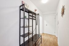 Heller Flur mit moderner Garderobe aus Holz und Metall, dekorativen Akzenten und stilvoller Wandgestaltung.