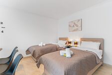 Wohnzimmer mit zwei hochwertigen Boxspringbetten und einem gemütlichen Essbereich. Die Betten können wahlweise einzeln oder als komfortables Doppelbett gestellt werden.