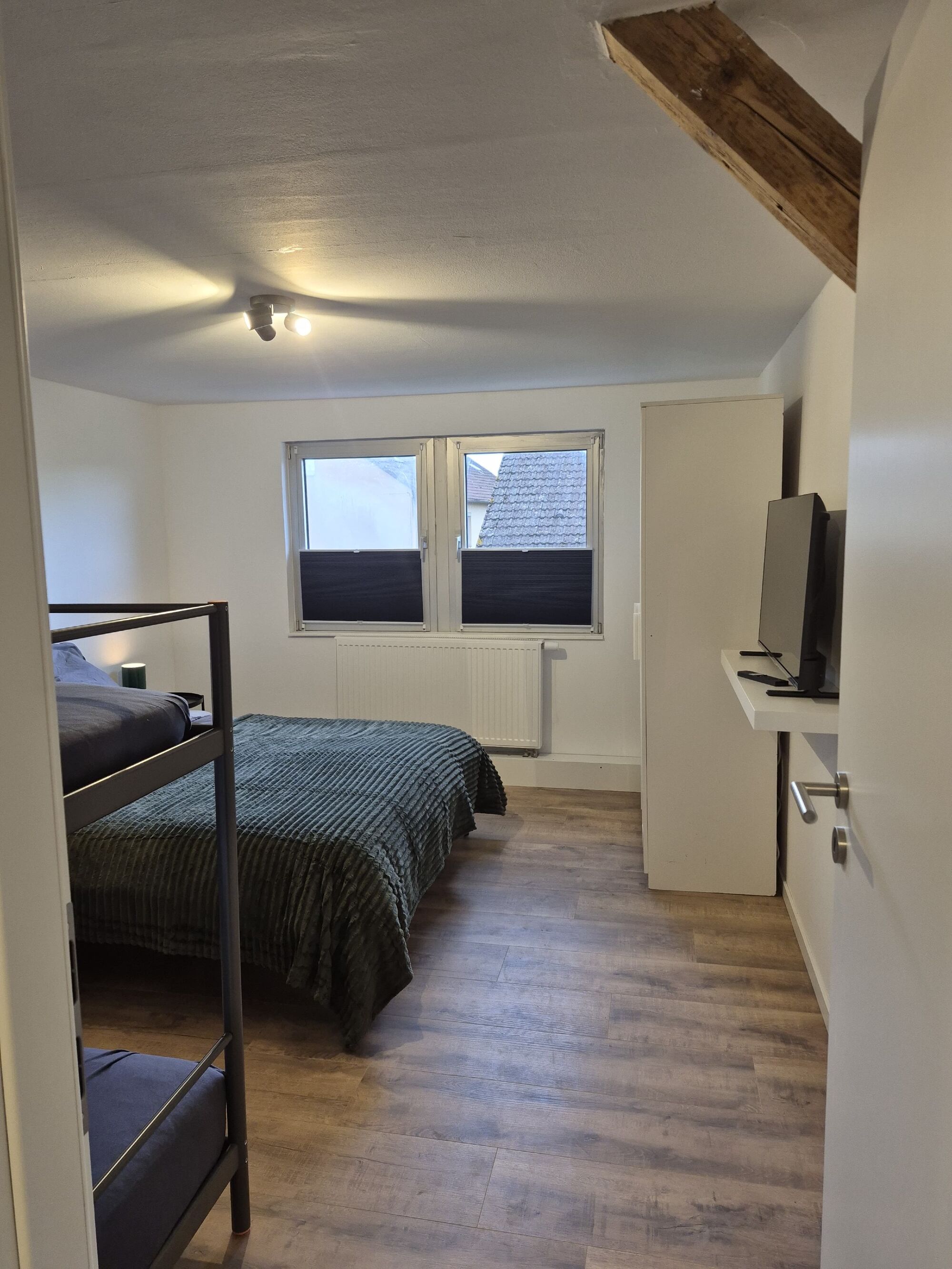 Schlafzimmer mit Doppelbett und Etagenbett, Schrank und TV