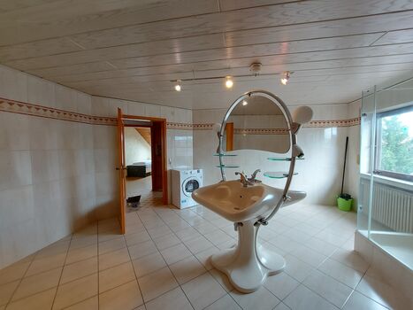 Das helle, einladende Bad lädt dazu ein, sich in entspannter Atmosphäre frisch zu machen. / The bright, inviting bathroom invites you to freshen up in a relaxed atmosphere.