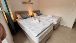 Helles Doppelzimmer mit zwei Einzelbetten, Balkonzugang und gemütlicher Beleuchtung. Modern eingerichtet mit Garderobe, Nachttischen und stilvollen Details – ideal für entspannte Übernachtungen.