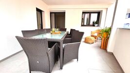 Großer, überdachter Balkon mit gemütlicher Sitzecke und Esstisch für bis zu acht Personen. Ideal zum Entspannen oder für gesellige Abende im Freien – stilvoll möbliert und dekoriert mit Pflanzen und Naturmaterialien.