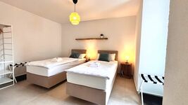 Gemütliches Doppelzimmer mit zwei Einzelbetten, stimmungsvoller Beleuchtung und Zugang zum Balkon. Helle Einrichtung, moderne Deko und ruhige Atmosphäre – perfekt zum Entspannen.
