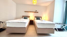 Gemütliches Doppelzimmer mit zwei Einzelbetten, stimmungsvoller Beleuchtung und Zugang zum Balkon. Helle Einrichtung, moderne Deko und ruhige Atmosphäre – perfekt zum Entspannen.