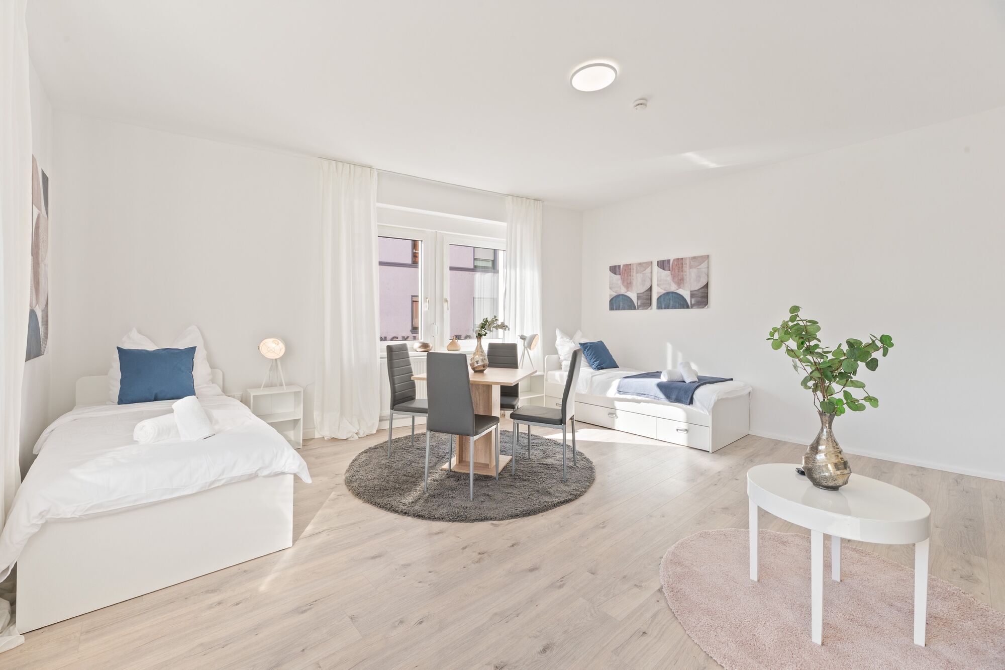 4-Zimmer-Wohnung: Zimmer 1 - Helles Zweibettzimmer mit zwei Einzelbetten. Ausgestattet mit 40 Zoll Smart-TV, Sofa und Sitzbereich mit Tisch. Viel Tageslicht.