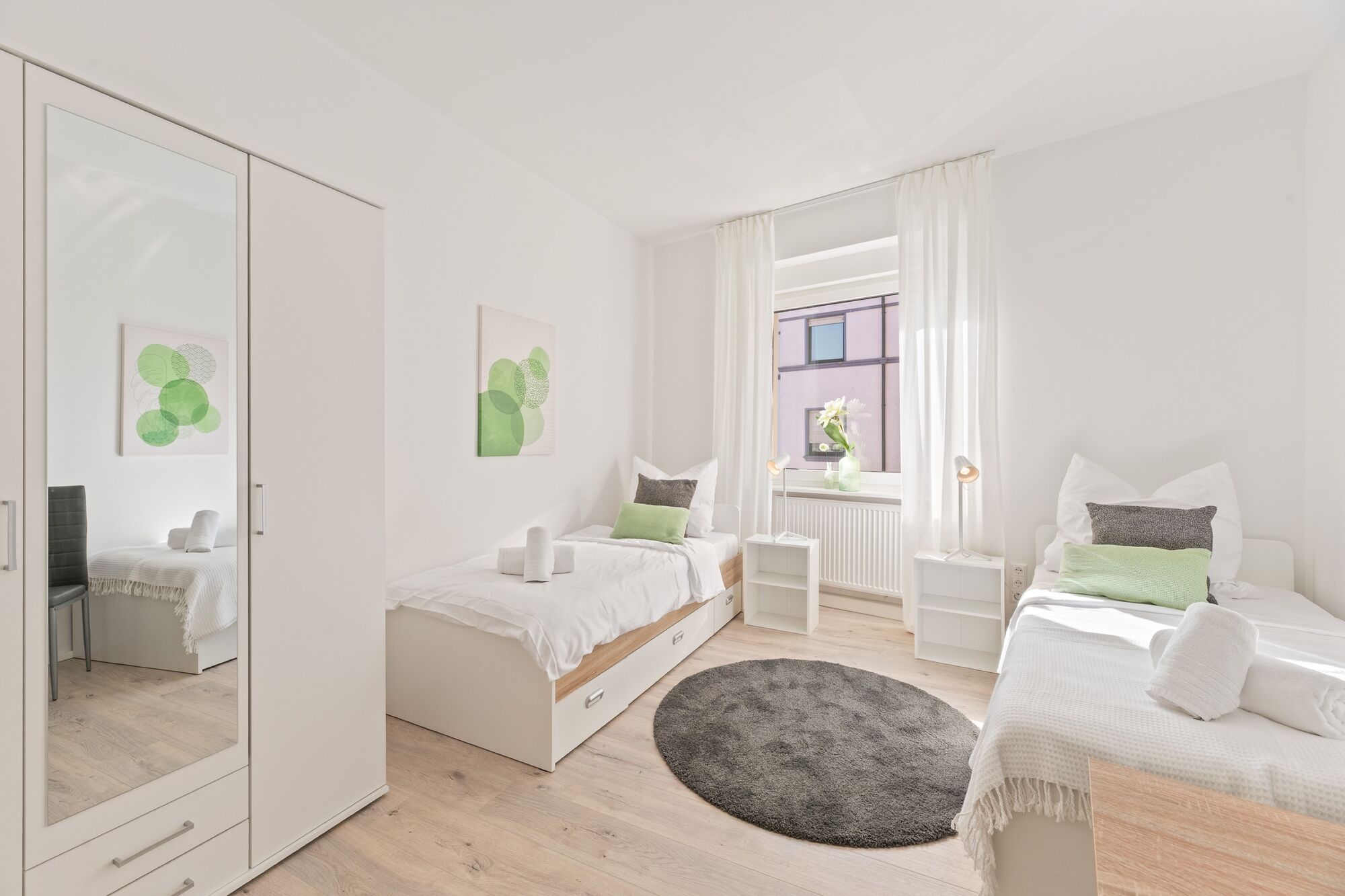 4-Zimmer-Wohnung: Zimmer 2 - Helles Zweibettzimmer mit zwei Einzelbetten. Ausgestattet mit Nachttischen, Kleiderschrank und 40 Zoll Smart-TV. Viel Tageslicht und funktionale Einrichtung.