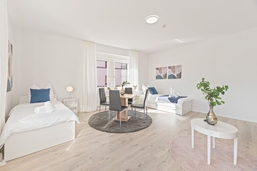 4-Zimmer-Wohnung: Zimmer 1 - Helles Zweibettzimmer mit zwei Einzelbetten. Ausgestattet mit 40 Zoll Smart-TV, Sofa und Sitzbereich mit Tisch. Viel Tageslicht.