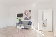 4-Zimmer-Wohnung: Zimmer - 1 Helles Zweibettzimmer mit zwei Einzelbetten. Ausgestattet mit 40 Zoll Smart-TV, Sofa und Sitzbereich mit Tisch. Viel Tageslicht.