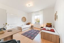 3-Zimmer-Wohnung: Zimmer 3 – Helles Zimmer mit zwei Einzelbetten. Ausgestattet mit 40 Zoll Smart-TV, Schreibtisch, Stuhl und Stauraum. Große Fenster sorgen für viel Tageslicht.