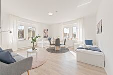 4-Zimmer-Wohnung: Zimmer 1 - Helles Zweibettzimmer mit zwei Einzelbetten. Ausgestattet mit 40 Zoll Smart-TV, Sofa und Sitzbereich mit Tisch. Viel Tageslicht.