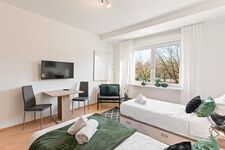 3-Zimmer-Wohnung: Zimmer 2 – Helles Zimmer mit zwei Einzelbetten. Ausgestattet mit 40 Zoll Smart-TV, Schreibtisch, Stuhl und Stauraum. Große Fenster sorgen für viel Tageslicht.