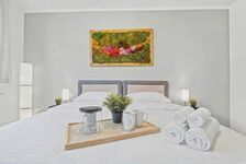 Doppelbett mit weißer Bettwäsche, buntes Moosgemälde an der Wand, Frühstückstablett auf dem Bett.
