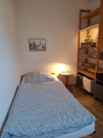 Kleines Schlafzimmer mit Einzelbett, Schreibtisch und Klappsessel